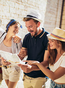 Group of tourists searching for places on their map outdoors.